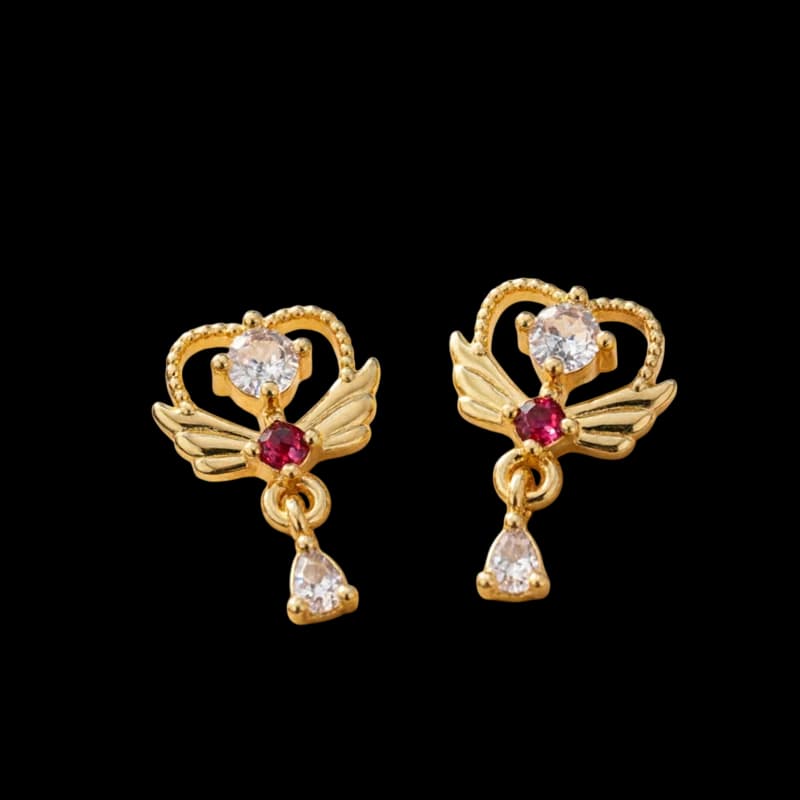 Golden-tone earrings with winged heart shapes, deep pink accents and clear teardrop pendants.
